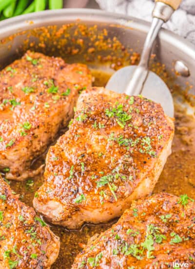 honey mustard pork chops on a skillet being flipped by a spatula