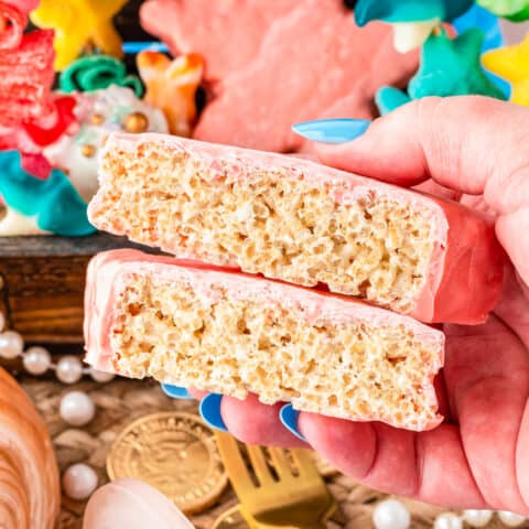 a hand holding a star shaped rice krispie treat that has been cut in half