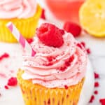 A raspberry lemon cupcake with a raspberry on top.