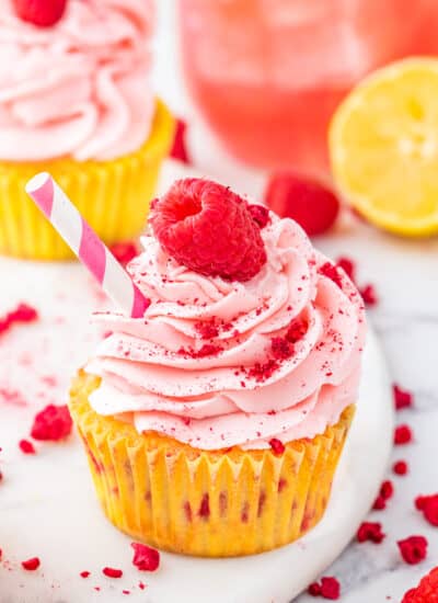 A raspberry lemon cupcake with a raspberry on top.
