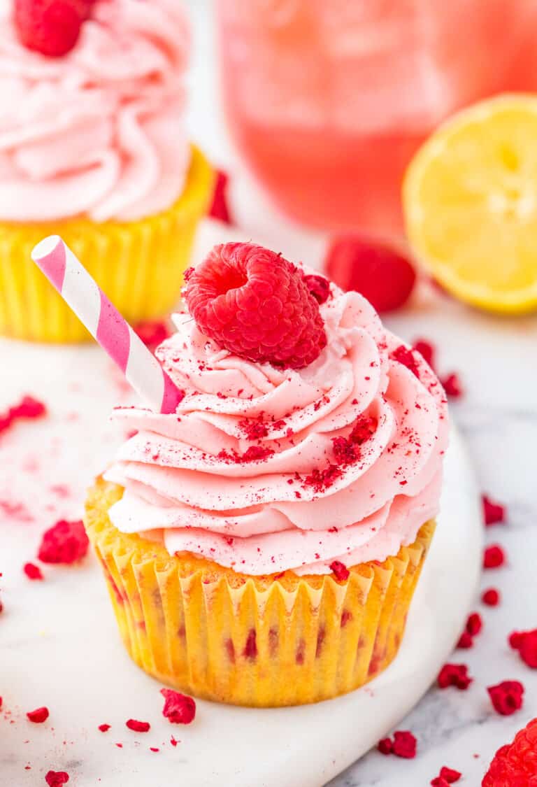 A raspberry lemon cupcake with a raspberry on top.