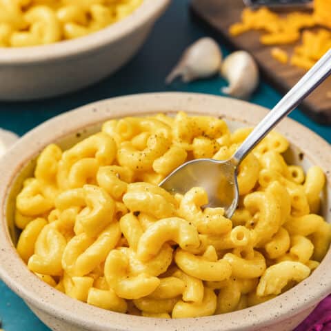 a bowl of butternut squash mac and cheese on a blue background