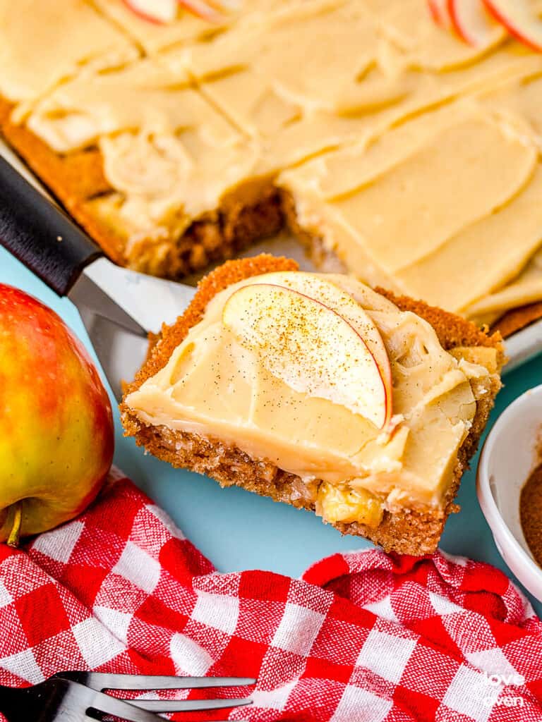 A slice of caramel apple cake being taken out of a pan