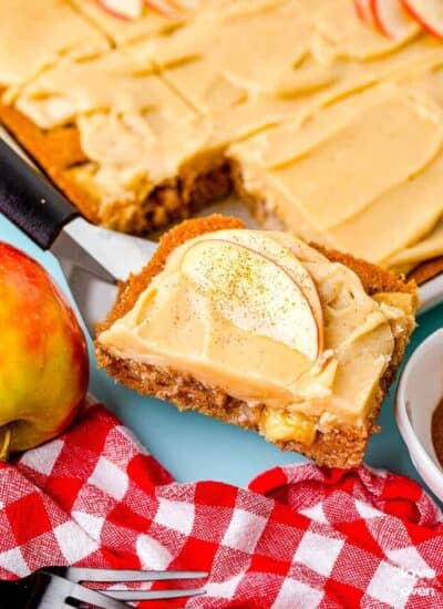 A slice of caramel apple cake being taken out of a pan