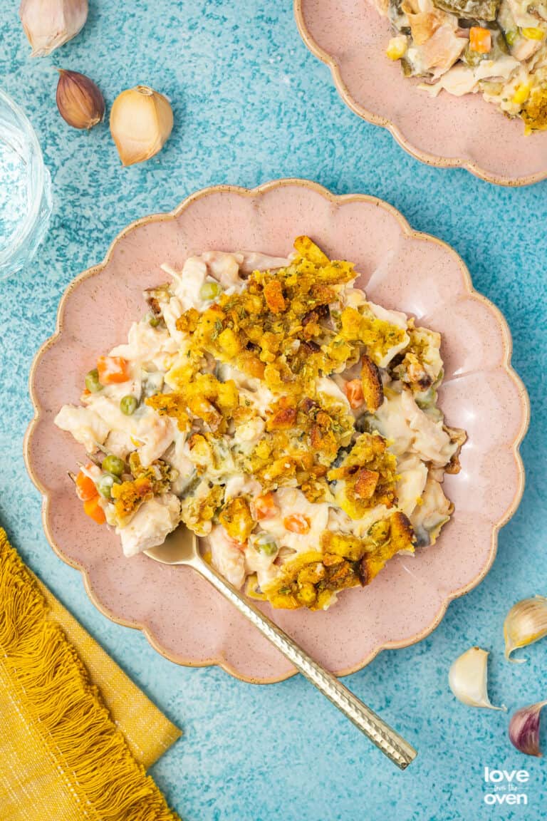 Chicken stuffing casserole on a pink plate on a blue background.