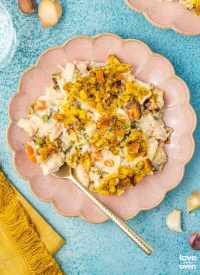 Chicken stuffing casserole on a pink plate on a blue background.