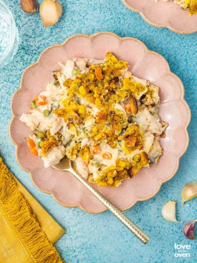 Chicken stuffing casserole on a pink plate on a blue background.