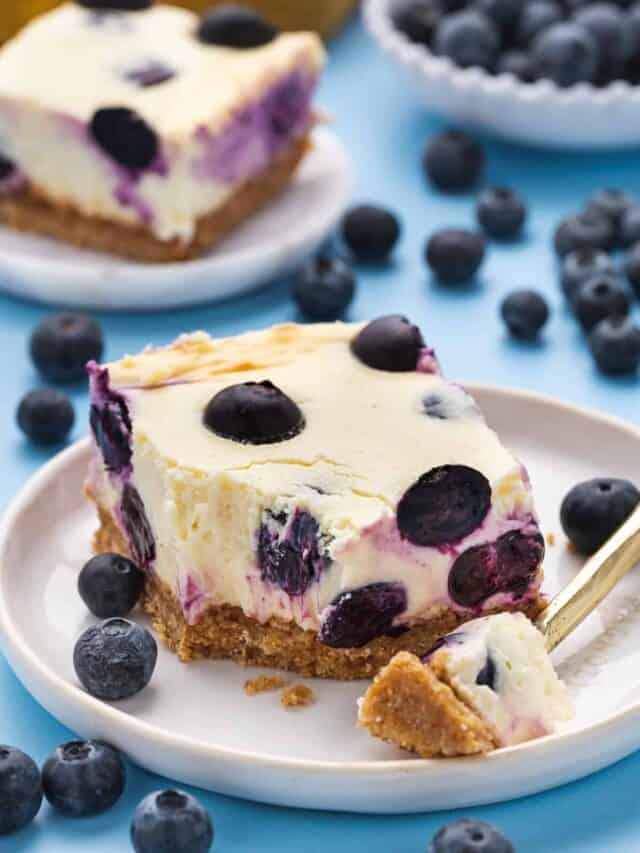 A slice of blueberry cheesecake on a plate with a fork.
