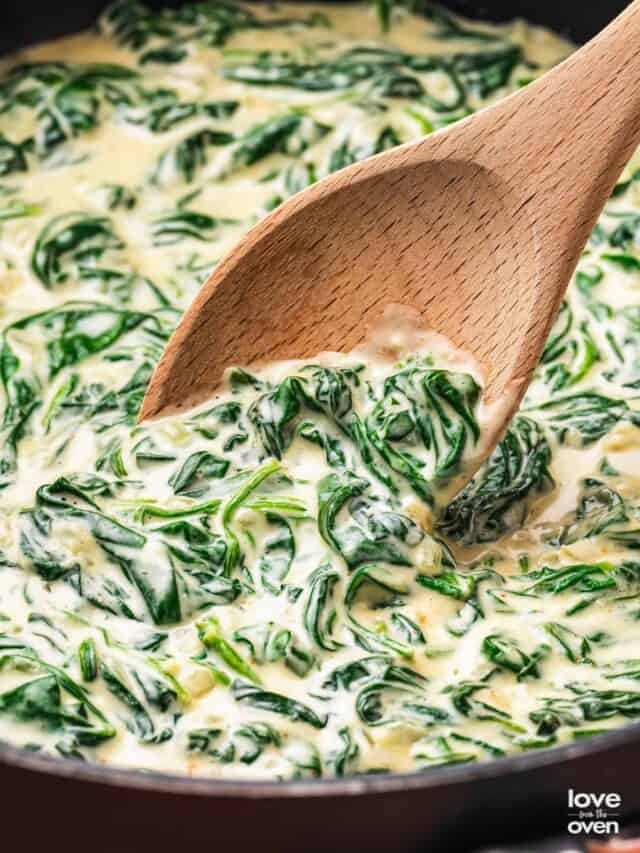 Creamed spinach in a pan with a wooden spoon
