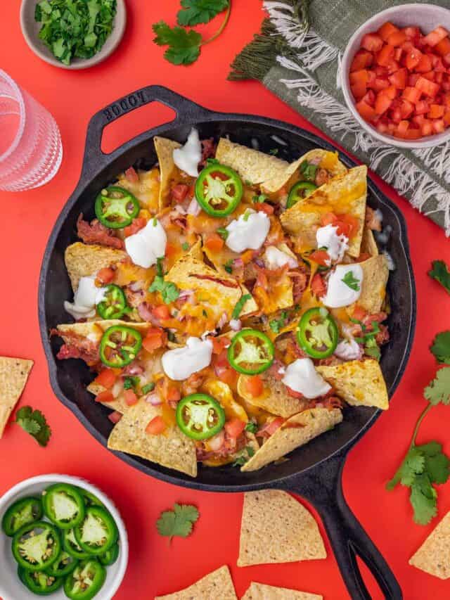 A cast iron skillet with pulled pork nachos in it
