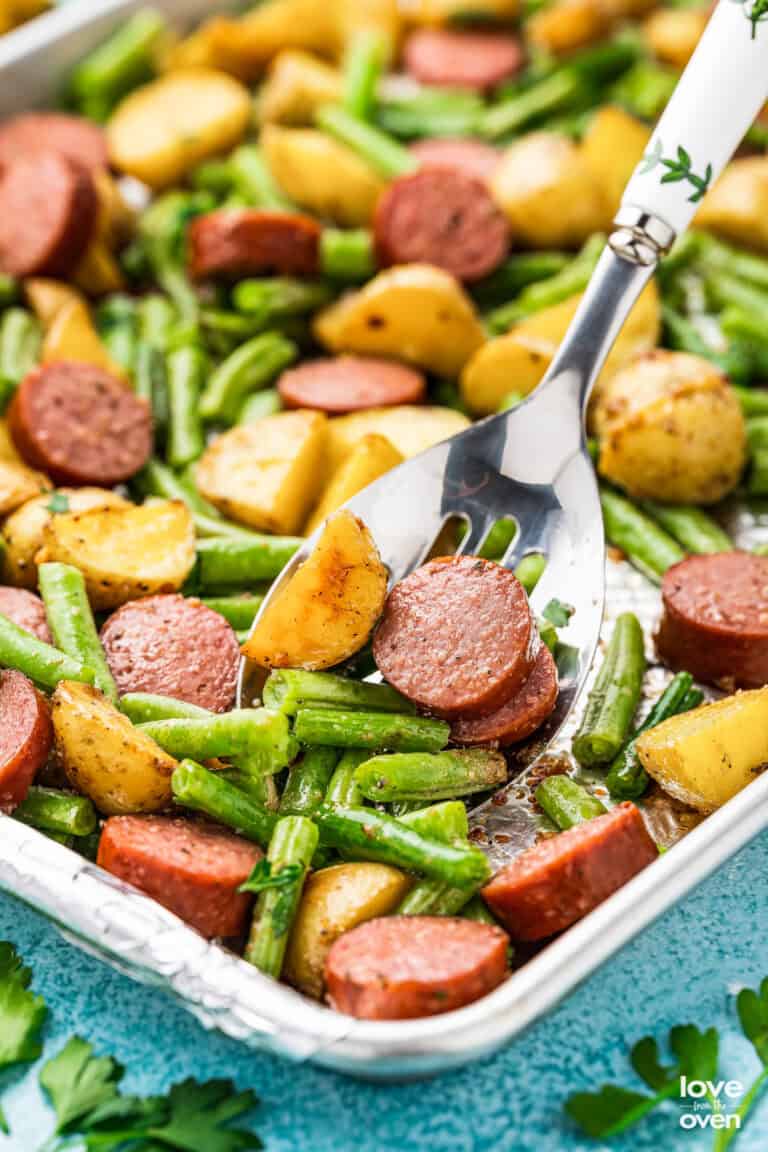 A sheet pan with smoked sausage, potatoes and green beans.
