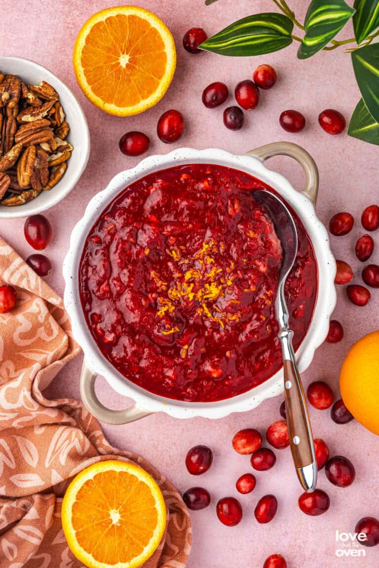 A bowl of cranberry orange relish surrounded by ingredients.