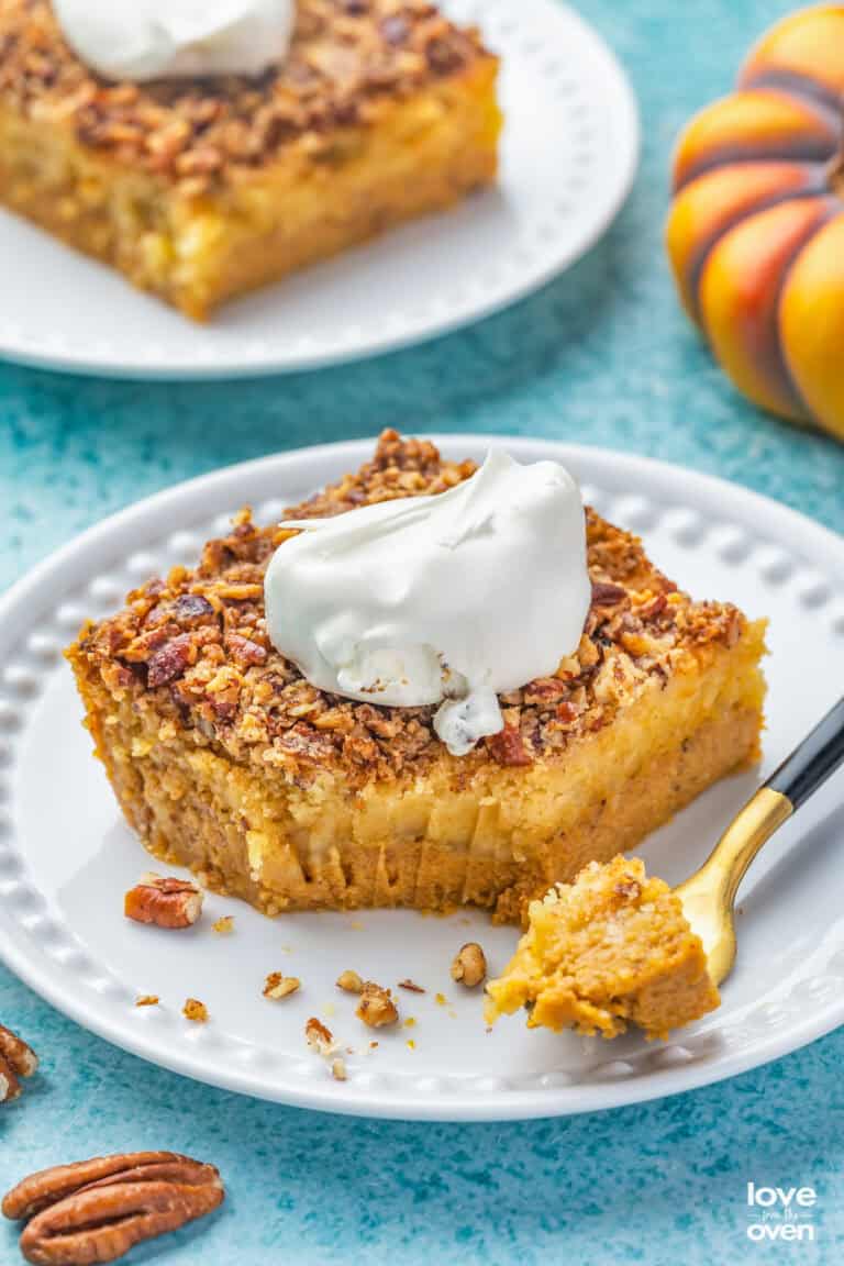 Slices of pumpkin crunch cake on white plates topped with whipped cream