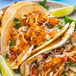 baja shrimp tacos with lime wedges on a plate