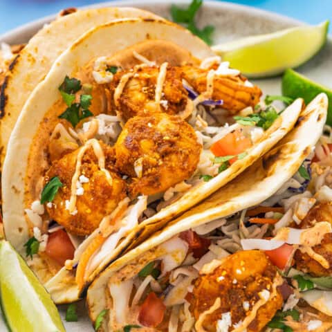 baja shrimp tacos with lime wedges on a plate