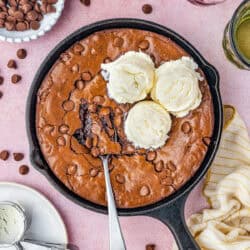 A skillet brownie with a spoon and three scoops of ice cream.