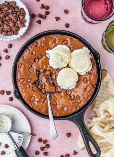 A skillet brownie with a spoon and three scoops of ice cream.