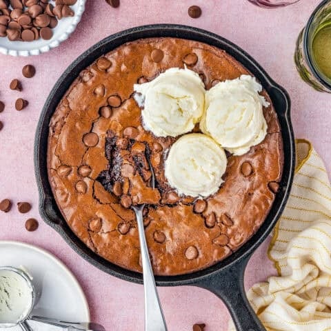A skillet brownie with a spoon and three scoops of ice cream.