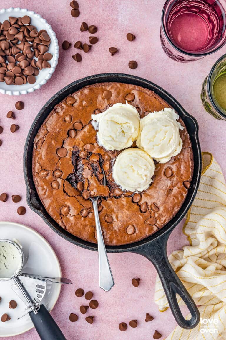 A skillet brownie with a spoon and three scoops of ice cream.