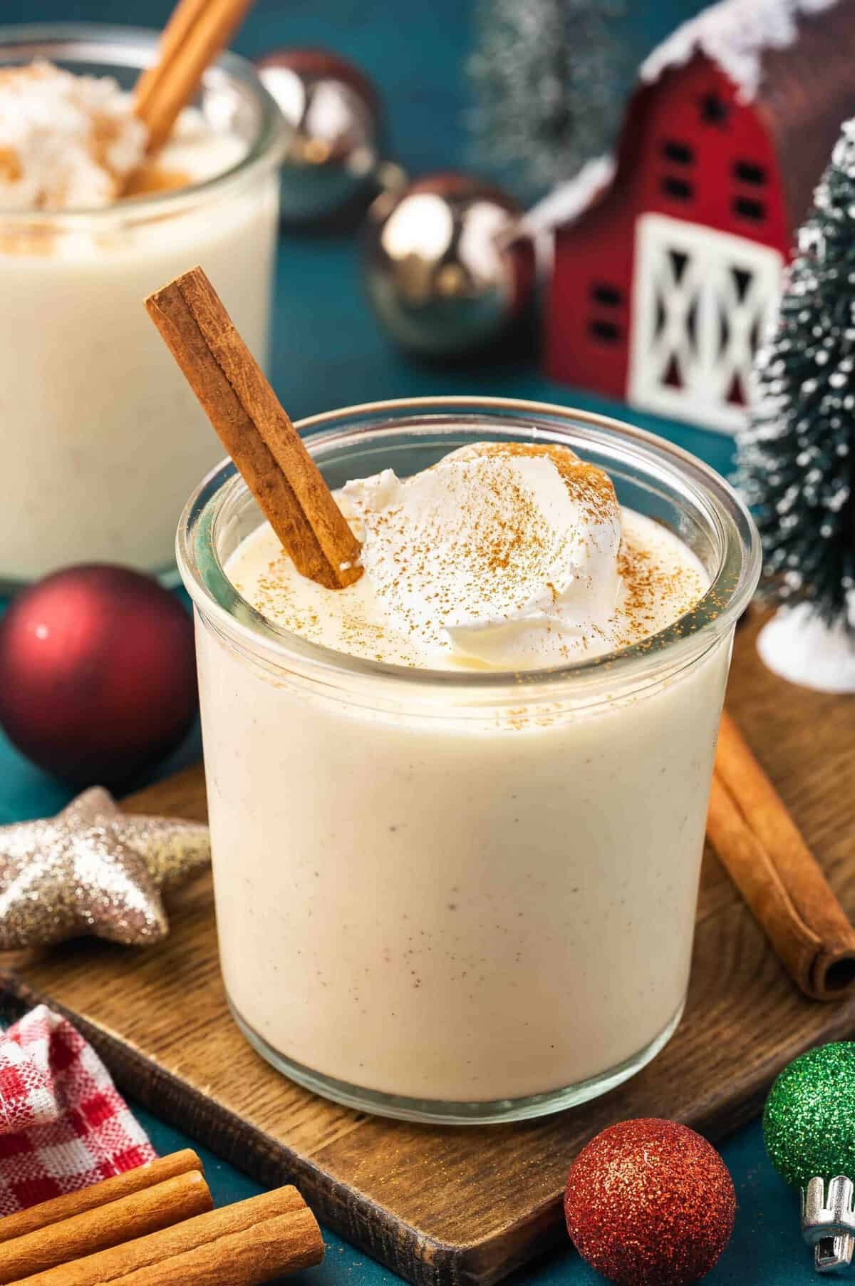 A glass of eggnog with whipped cream and a cinnamon stick