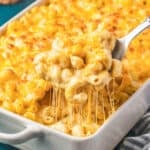 A spoon taking a scoop of Tinis Mac and Cheese out of a white casserole dish