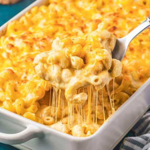 A spoon taking a scoop of Tinis Mac and Cheese out of a white casserole dish