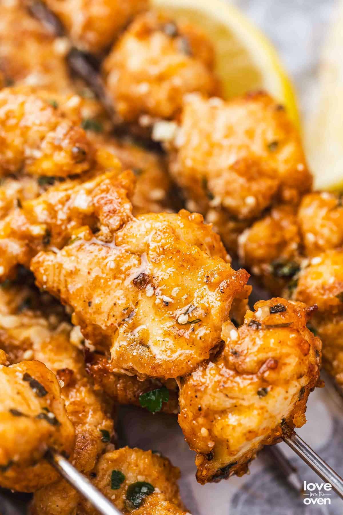 A super close image of chunks of cooked chicken on skewers