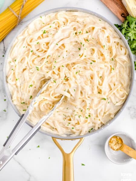 A pan with pasta and Alfredo sauce.