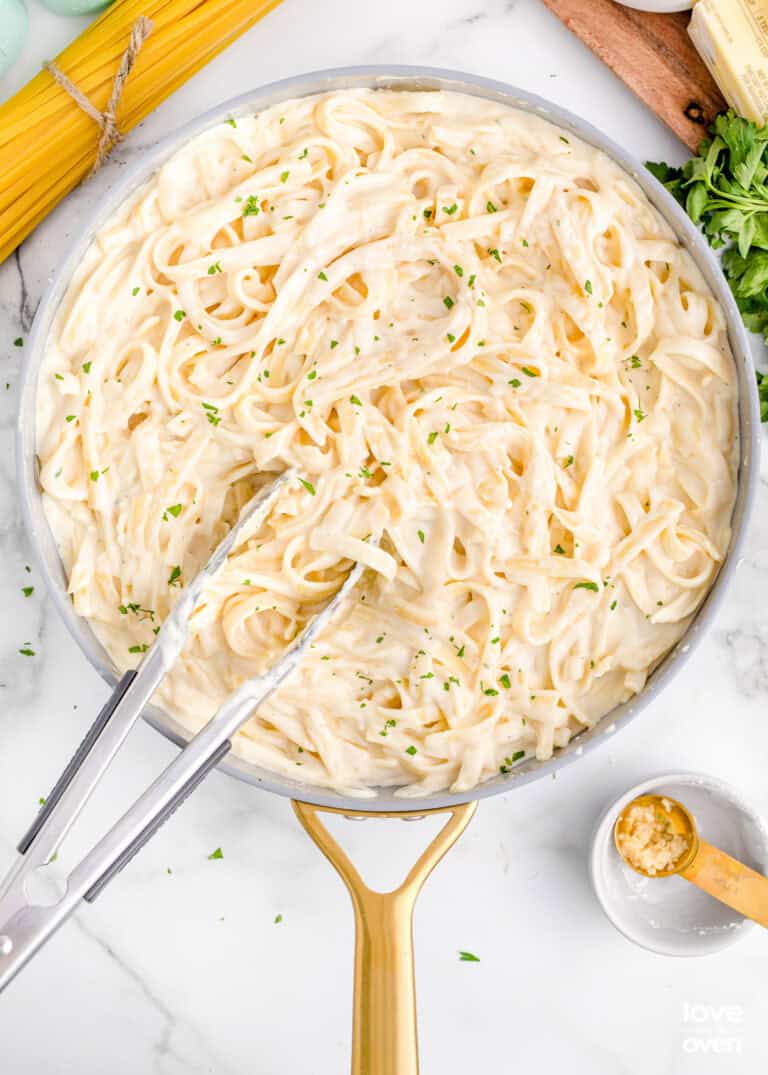 A pan with pasta and Alfredo sauce.