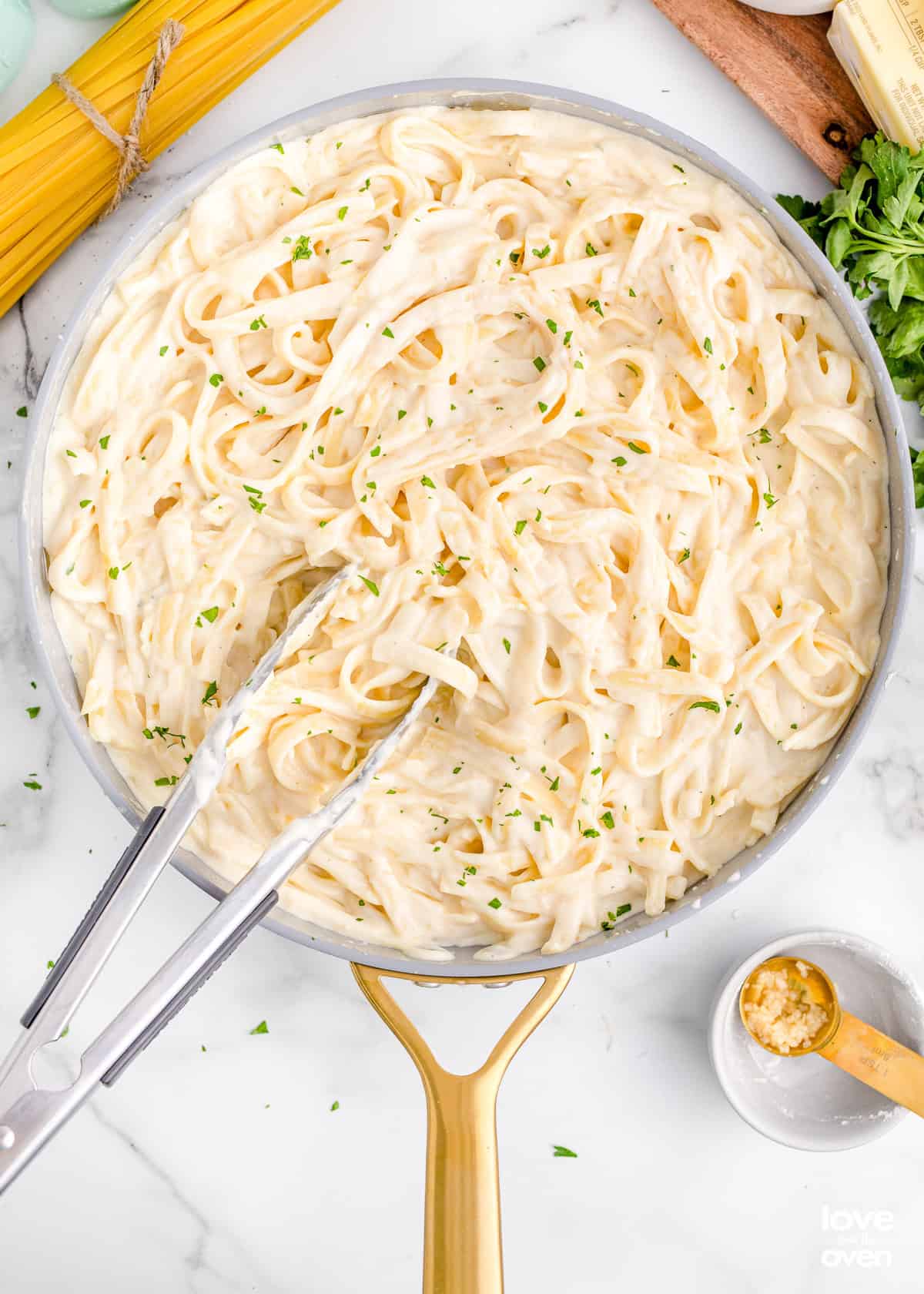 A pan with pasta and Alfredo sauce.