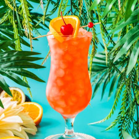 a hurricane cocktail topped with an orange slice and cherry