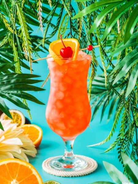 a hurricane cocktail topped with an orange slice and cherry