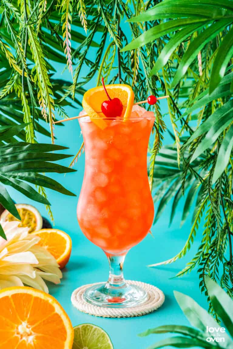 a hurricane cocktail topped with an orange slice and cherry