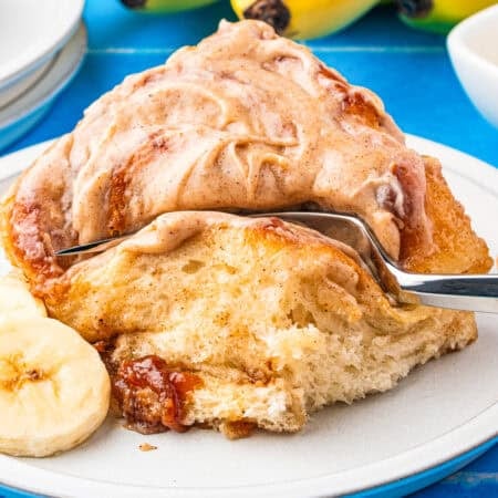A banana bread cinnamon roll with a fork cutting a piece off