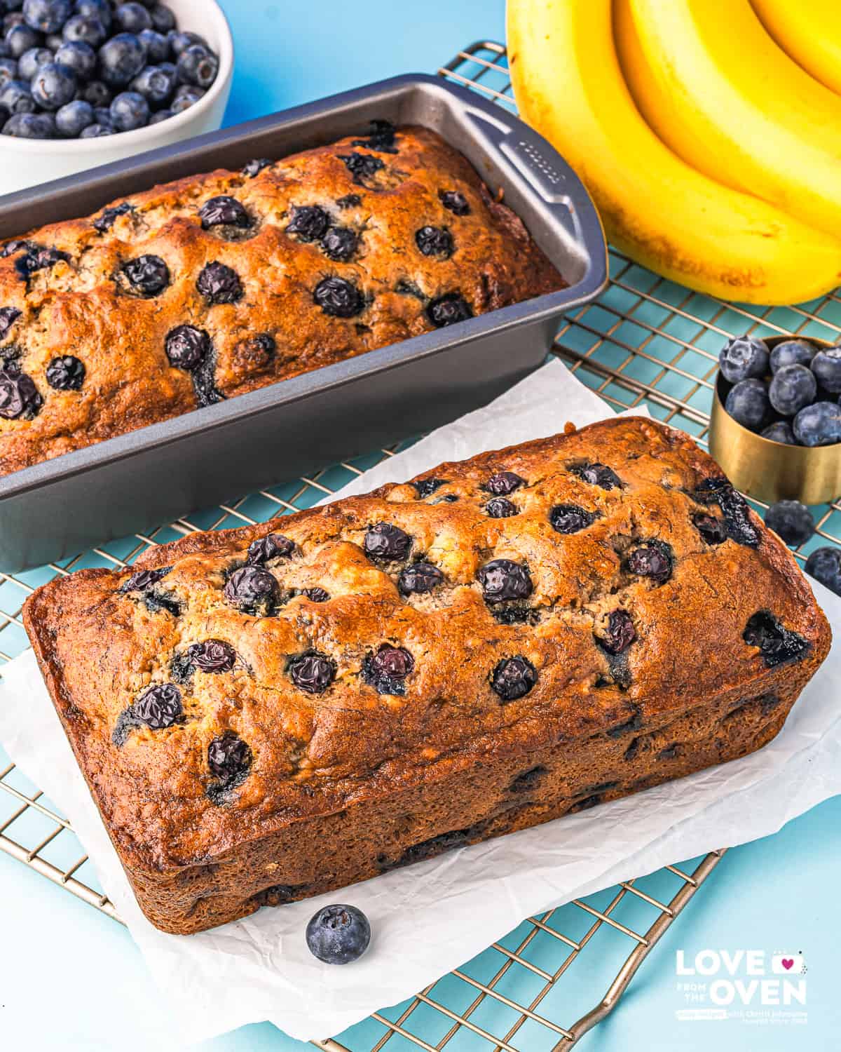 Two loaves of blueberry banana bread, one in a pan.