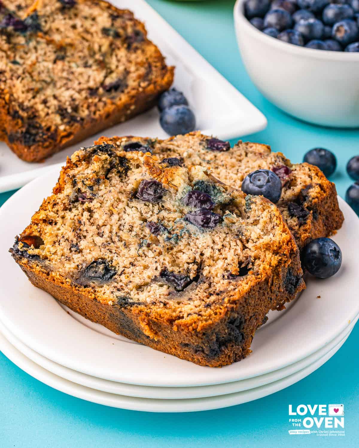 Two slices of blueberry banana bread on a stack of plates.