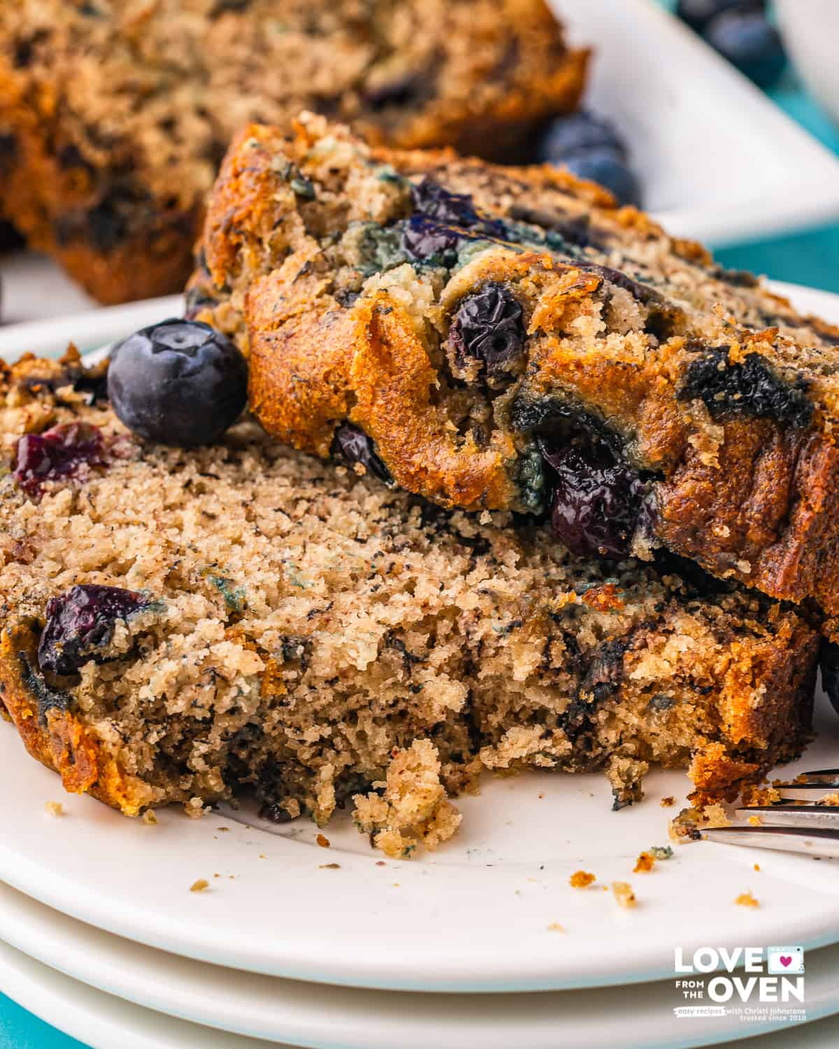 Two slices of banana bread on a plate, one with a bite taken out of it.