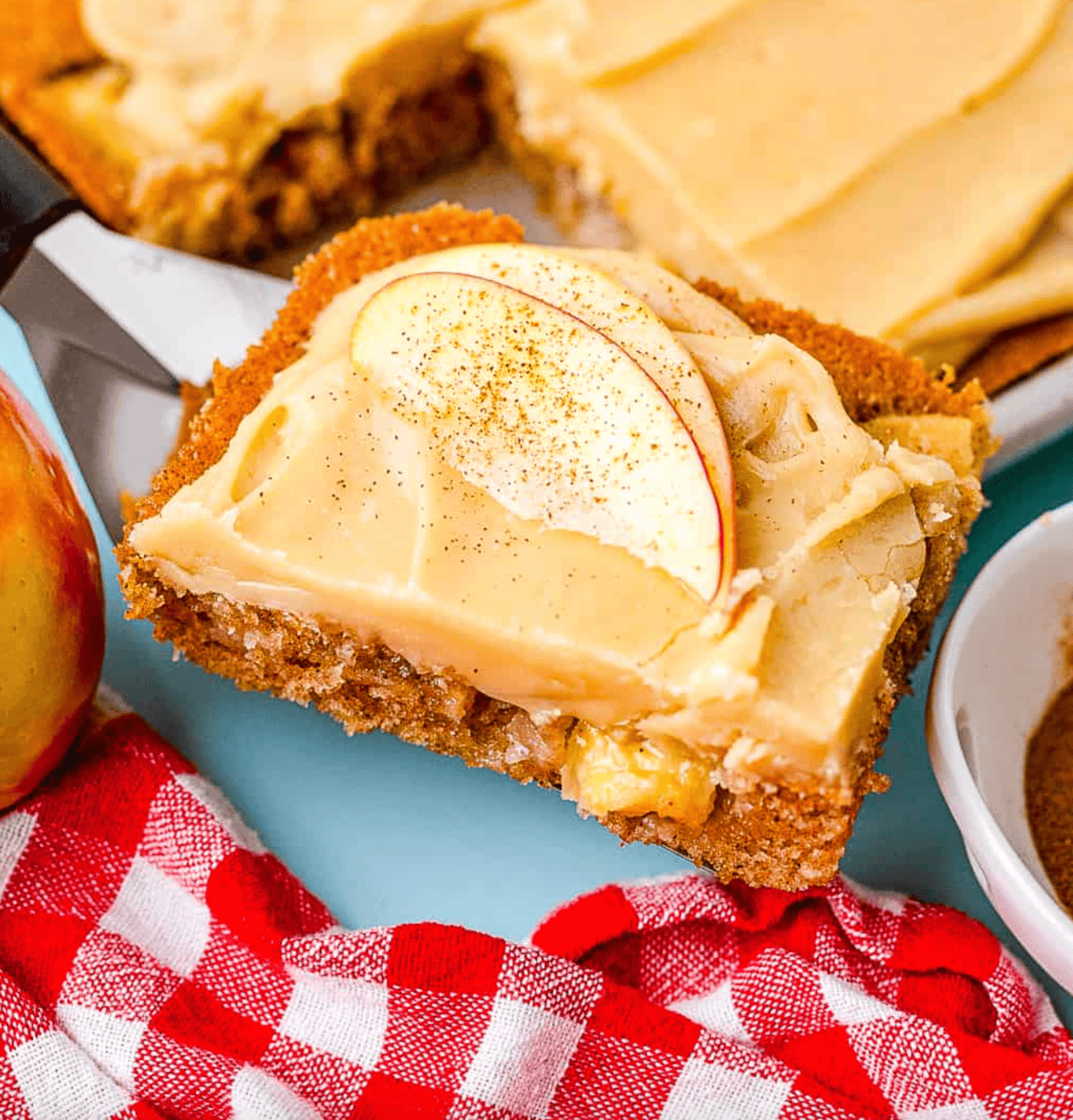 A piece of an apple sheet cake being lifted with a spatula.